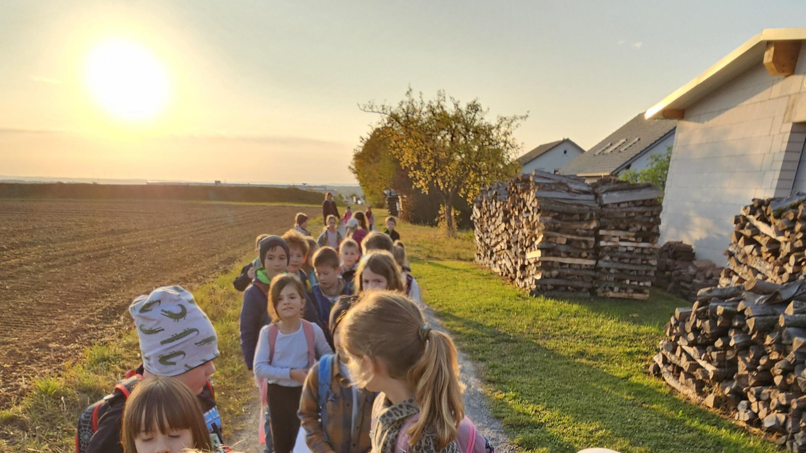 Gruppe Kinder auf einem Feldweg bei Sonnenuntergang.